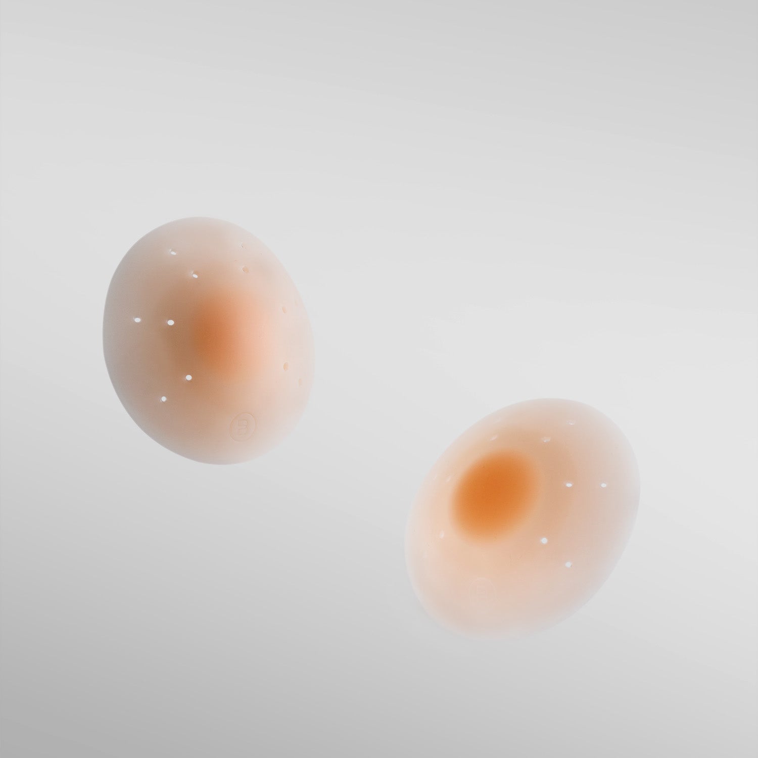 Pair of Essential silicone petals in nude shade on white background with breathe points and adhesive-free center.